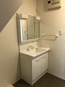 落ち着いた床に真っ白な洗面台が映える脱衣所